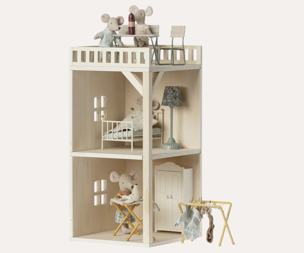 Toy dollhouse with furniture and toy figures on a white background