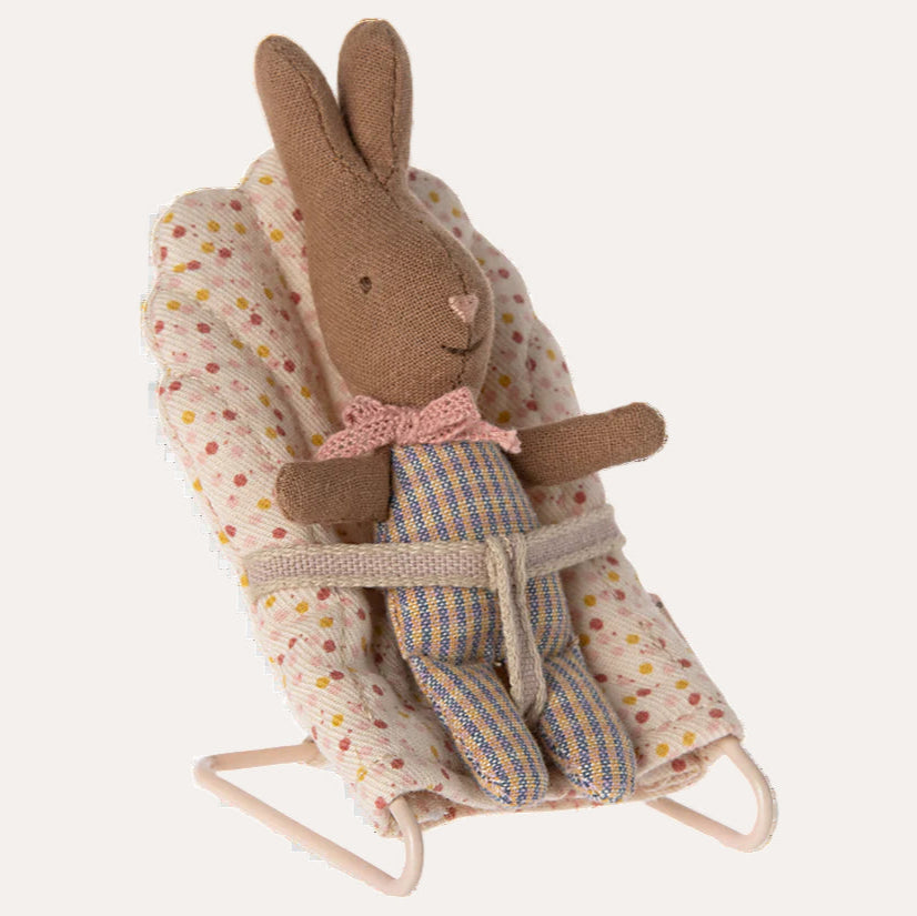 Stuffed rabbit toy in a bouncer with a polka dot cover on a white background