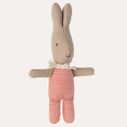 Stuffed toy rabbit with a beige sweater and red checkered pants on a white background