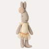 Stuffed rabbit toy with a yellow dress and pink bow on a white background