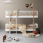 Oliver Furniture Original low bunk bed in White/Oak with a left-hand ladder, styled with bedding, cushions and toys.