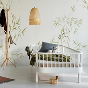 Oliver Furniture white Original day bed styled with cushions and bedding against a leaf-patterned wall.