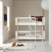 Oliver Furniture Mini+ low bunk bed in White/Oak with a right-hand ladder, styled with bedding in a pale bedroom.