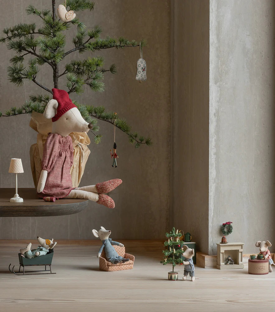 Decorative scene with small figurines and a miniature tree in a room with large windows.