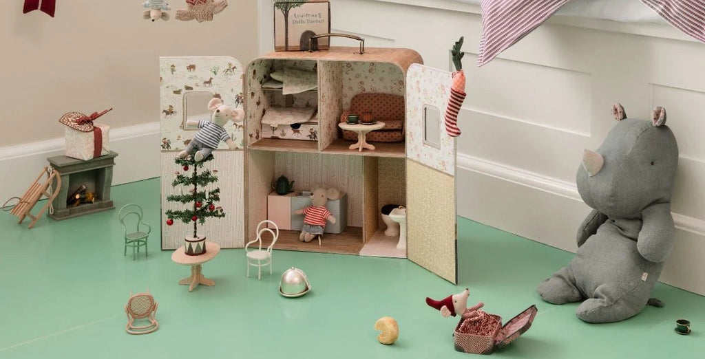Children's room with a dollhouse, toys, and a bed with pink bedding.
