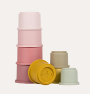 Little Dutch Pink Stacking Cups arranged in a tall pink stack with yellow, green and beige cups beside it.