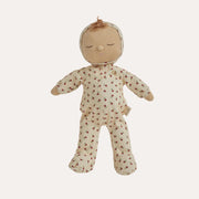 A sleeping doll with a beige fabric head and arms, wearing a cream-colored footed onesie with a small red floral pattern, set against a plain white background.