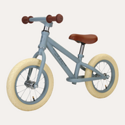 Little Dutch Blue Matte Balance Bike in front three-quarter view with cream tyres and brown saddle and grips.