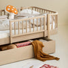 Children's wooden bed with storage drawers and bedding in a room setting.