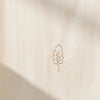 A square beige fabric or paper product with a small minimalist tree outline printed in the center, shown against a white background with soft shadow overlays.