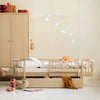 Children's room with wooden children's bed and wardrobe against a beige wall.
