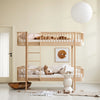 Wooden bunk bed in a minimalistic room with a lamp and artwork on the wall.