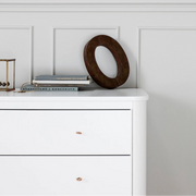 White dresser with decorative items against a paneled wall.