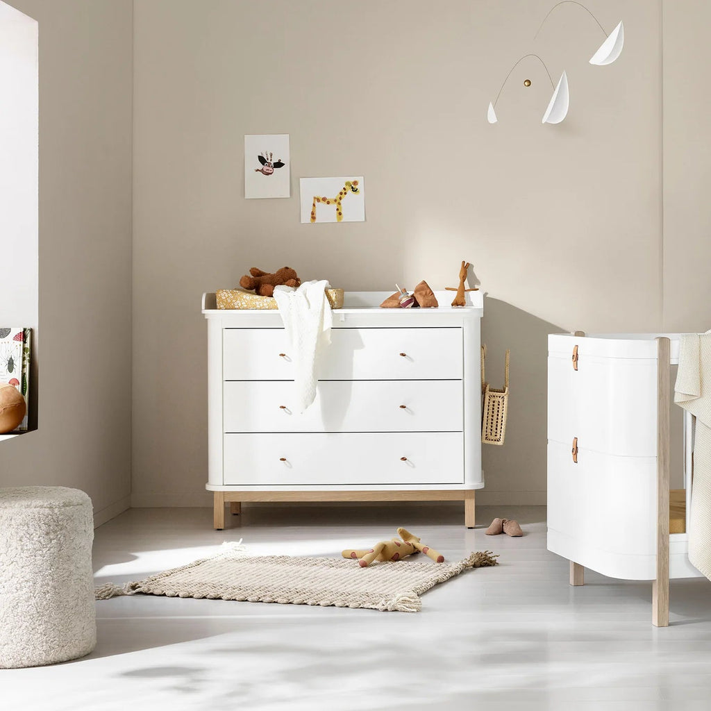 Nursery room with white dresser, toys, and decorative elements.