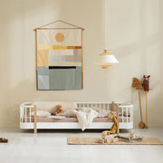 Oliver Furniture Wood Original Floor Bed in White/Oak, beneath a colourful wall hanging.