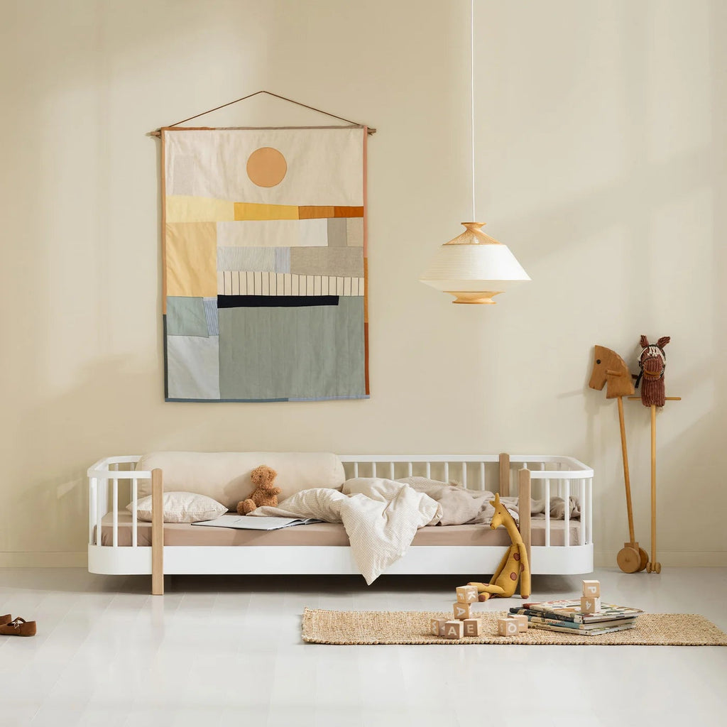 Children's room with a white crib, colorful wall hanging, and wooden toys.