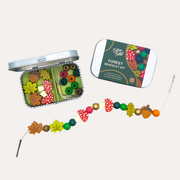 Cotton Twist Forest Bracelet Gift Kit with an open tin of beads, its lid and a strand of mushroom and leaf beads.
