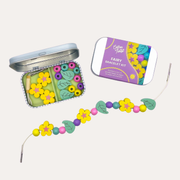 Cotton Twist Fairy Bracelet Gift Kit with an open tin of beads and a strand of yellow flowers, green leaves and round beads.