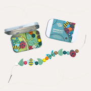Cotton Twist Minibeast Bracelet Gift Kit with an open tin, teal lid and a strand of insect, leaf and round beads.