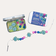 Cotton Twist Mermaid Bracelet Gift Kit with an open tin, blue lid and a strand of shell-shaped and colourful round beads.