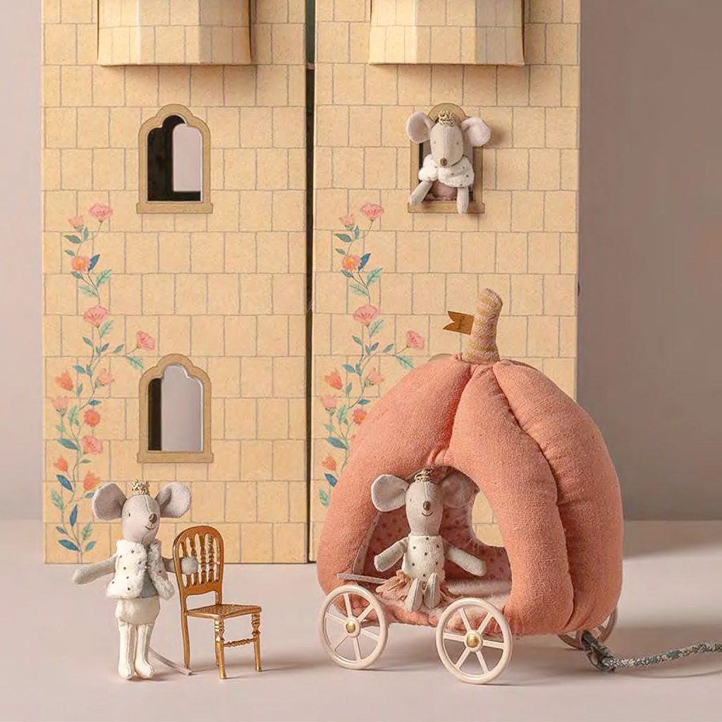 Toy mouse family with a pink pumpkin carriage in front of a toy castle.