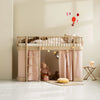 A light natural wood loft bed with pink fabric curtains and a ladder, styled in a child's bedroom with toys, a small stool, and soft wall decals.