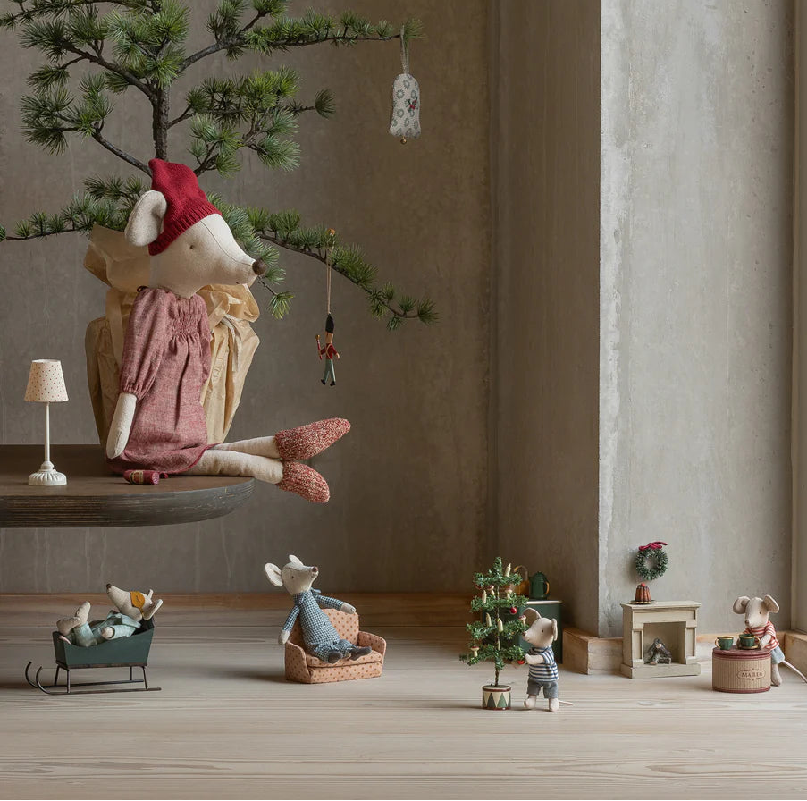 Decorative scene with small figurines and a miniature tree in a room with large windows.