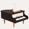 Black toy piano with music stand on a white background