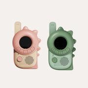 The Zoofamily Dino Pink and Green walkie-talkies shown side by side with round black screens and dinosaur-shaped edges.