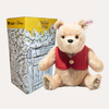 Plush bear toy with a red vest in front of a Disney Winnie the Pooh box.