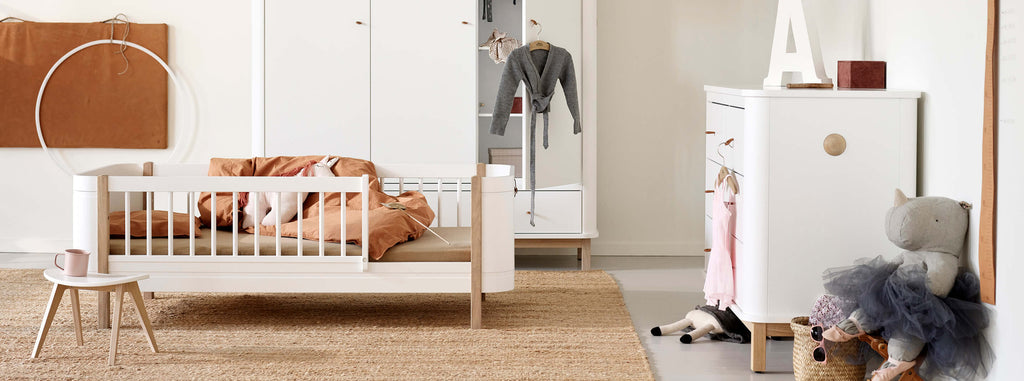 Nursery room with white crib, wardrobe, and dresser.