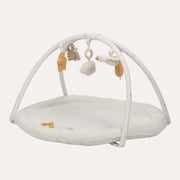 Little Dutch Newborn Naturals activity play mat with a round cream base, crossed arches and hanging toys.