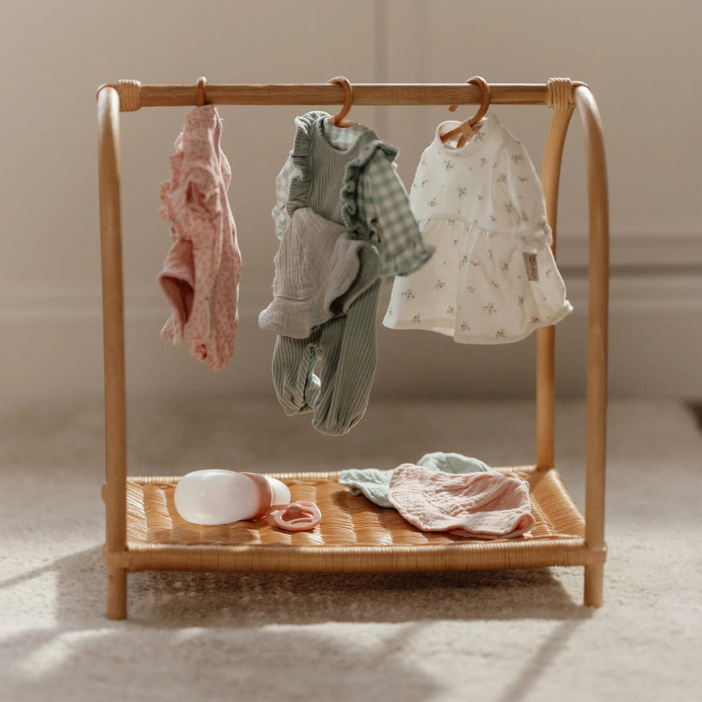 Wooden baby clothes rack with hanging baby clothes on a neutral background