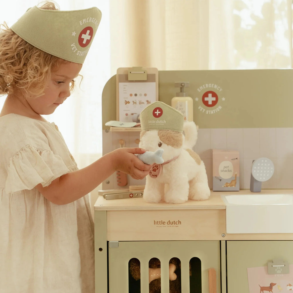 Child playing with a toy doctor set including a teddy bear and medical station.