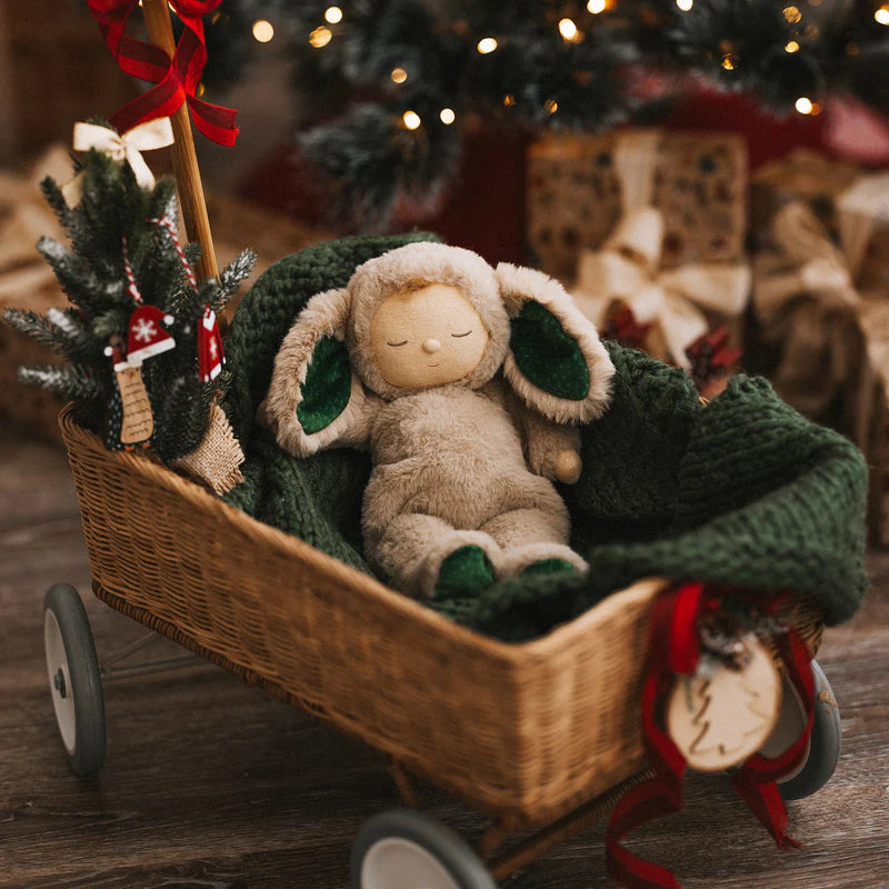 Toy rabbit in a small cart with a Christmas tree and lights in the background