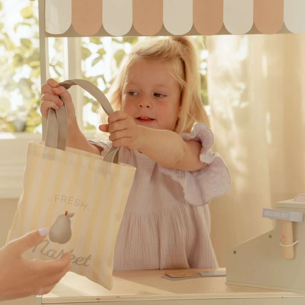 Child holding a striped bag with a person's hand, set against a blurred outdoor background.