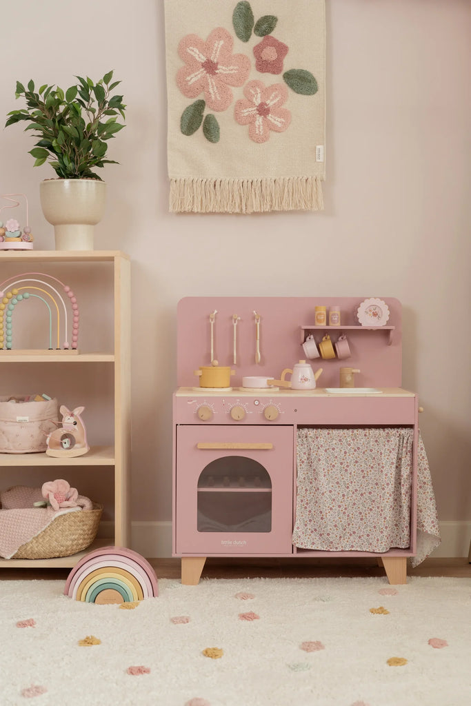 Children's pink play kitchen with accessories in a room setting.