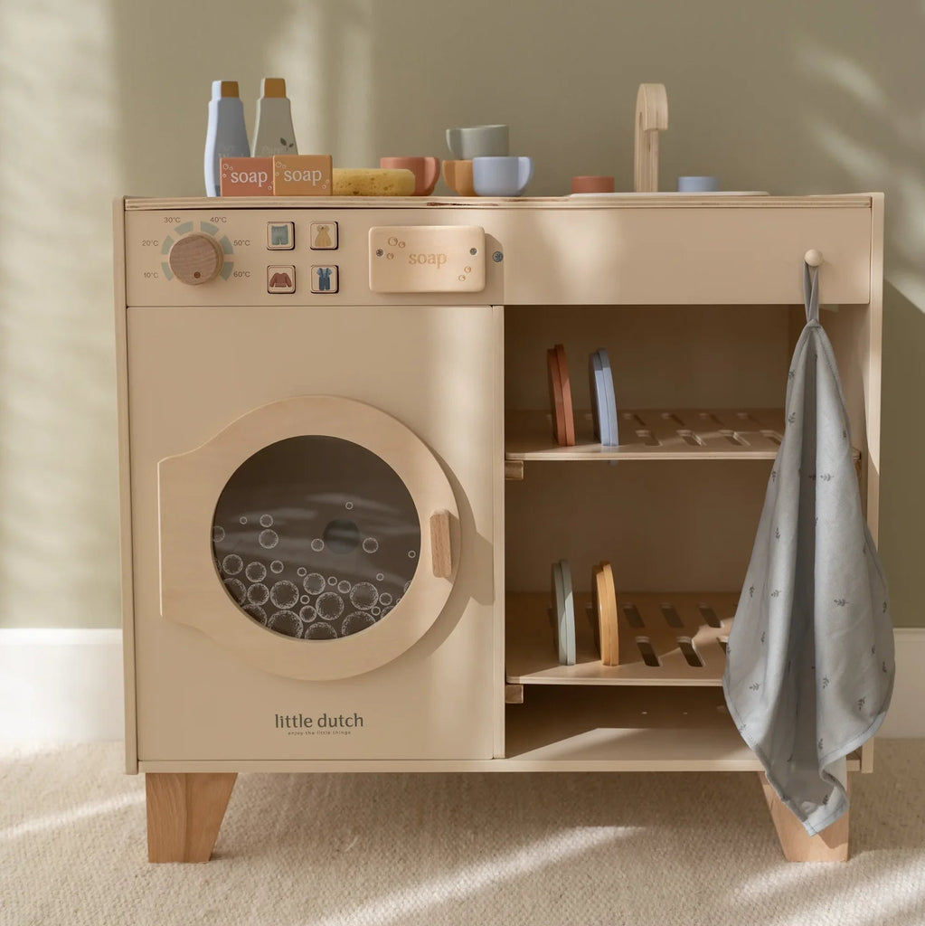 Wooden toy washing machine with shelves and a towel on a neutral background